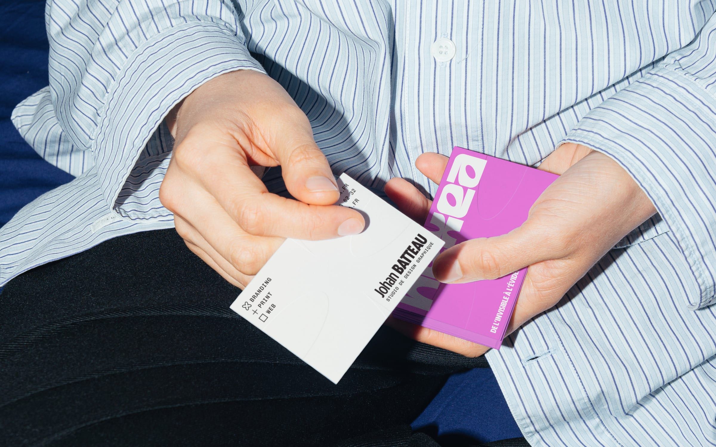 Cartes de visite Nexea tenues en main, sur une chemise rayée